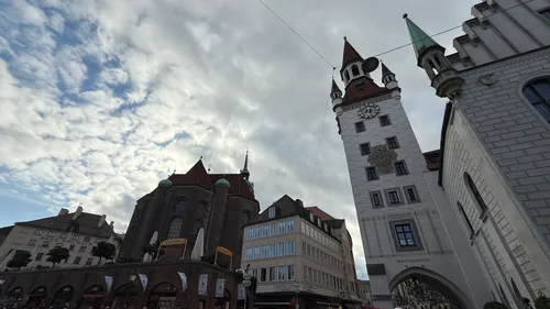 Historische Gebäude mit hohem Turm unter bewölktem Himmel.