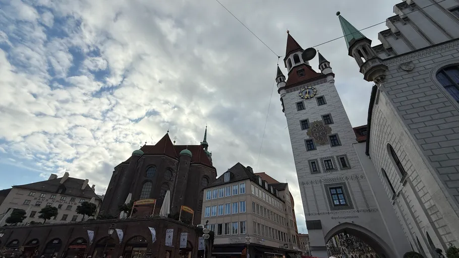 Historische Gebäude mit hohem Turm unter bewölktem Himmel.