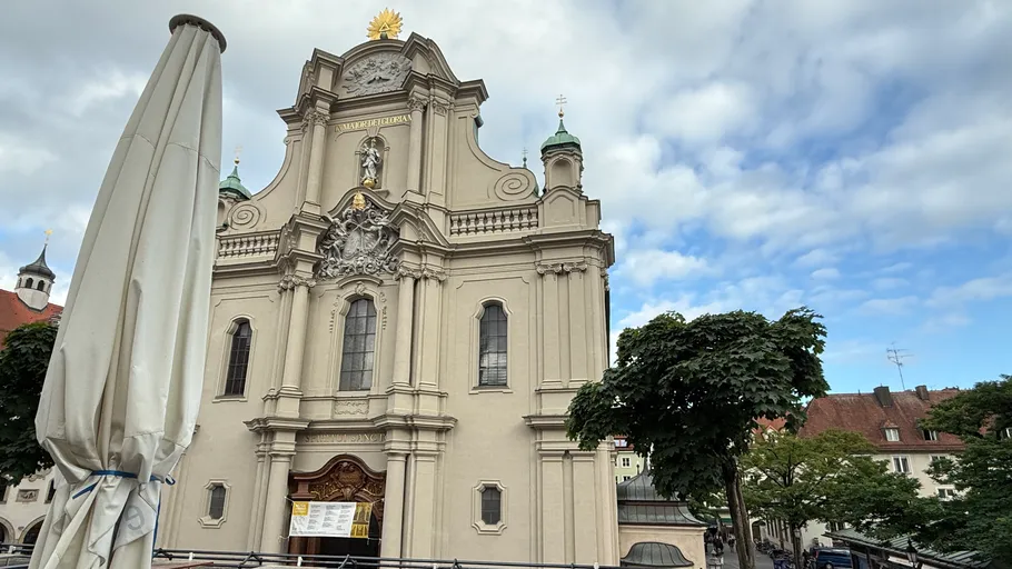 Baroque church facade with cloudy sky.