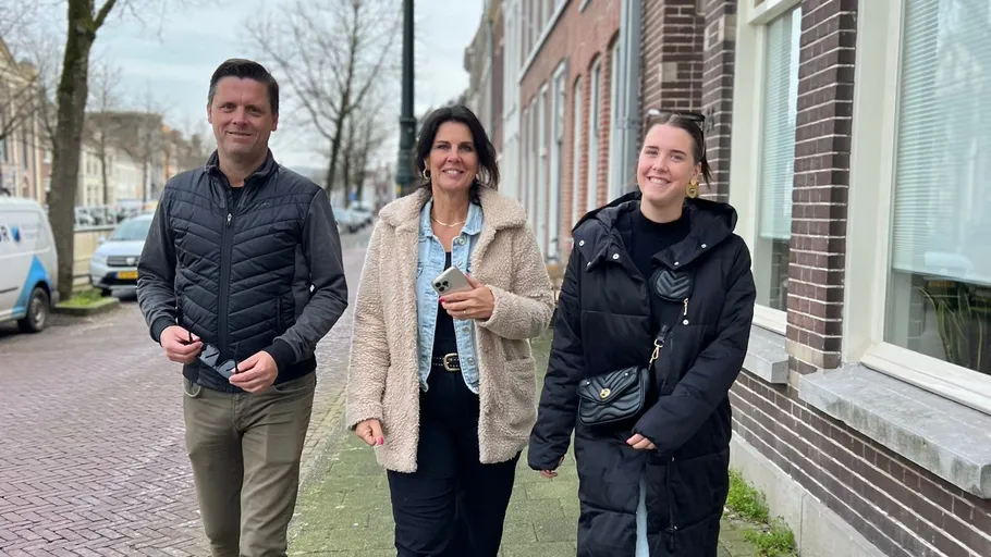 Three people walking on a city sidewalk.