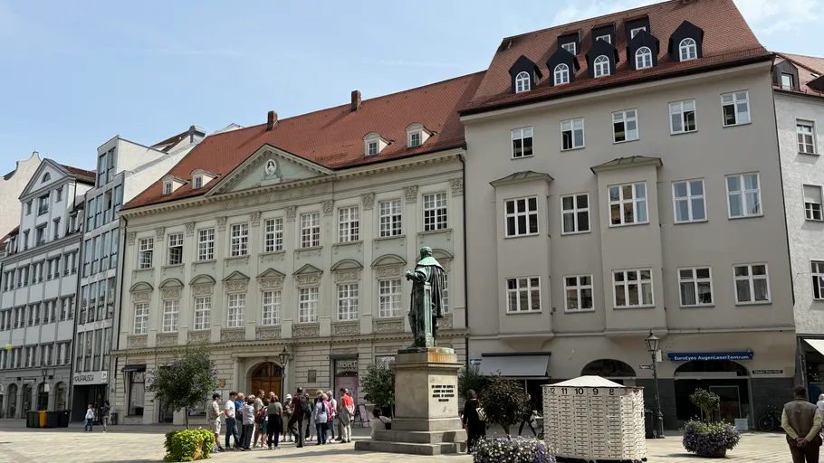 Statue in courtyard with surrounding buildings.