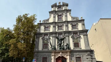 Ornate building facade with statues and trees.