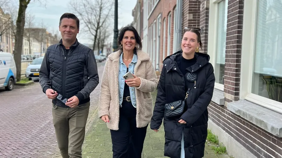 Three people walking on a city sidewalk.