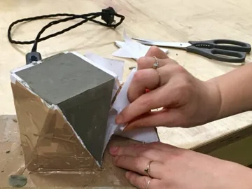 Jemand entfernt Papier von einem Betonblock auf einem Tisch.
