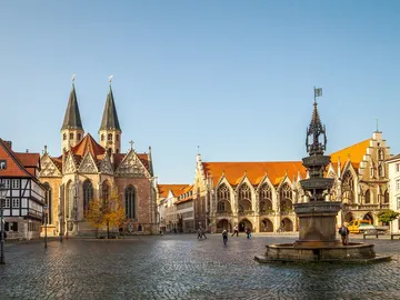 A church with two towers stands in the sunny town square.
