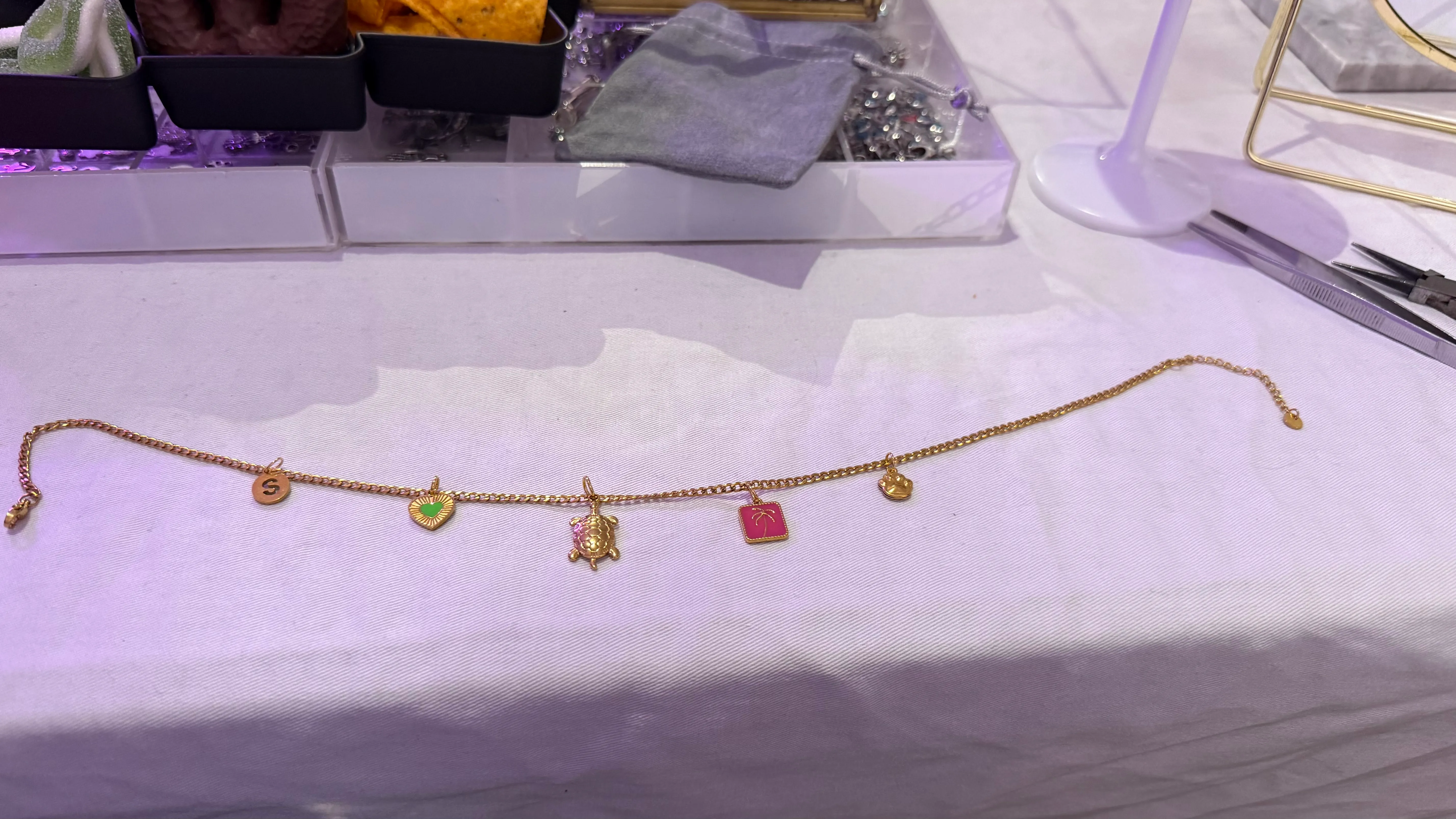 Goldenes Armband mit verschiedenen Anhängern auf Tisch.