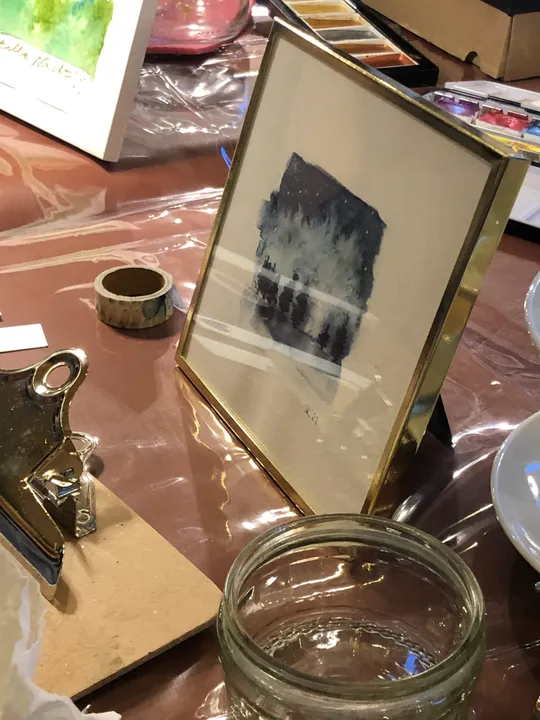 Gerahmtes Bild auf Tisch mit Kunstmaterialien.