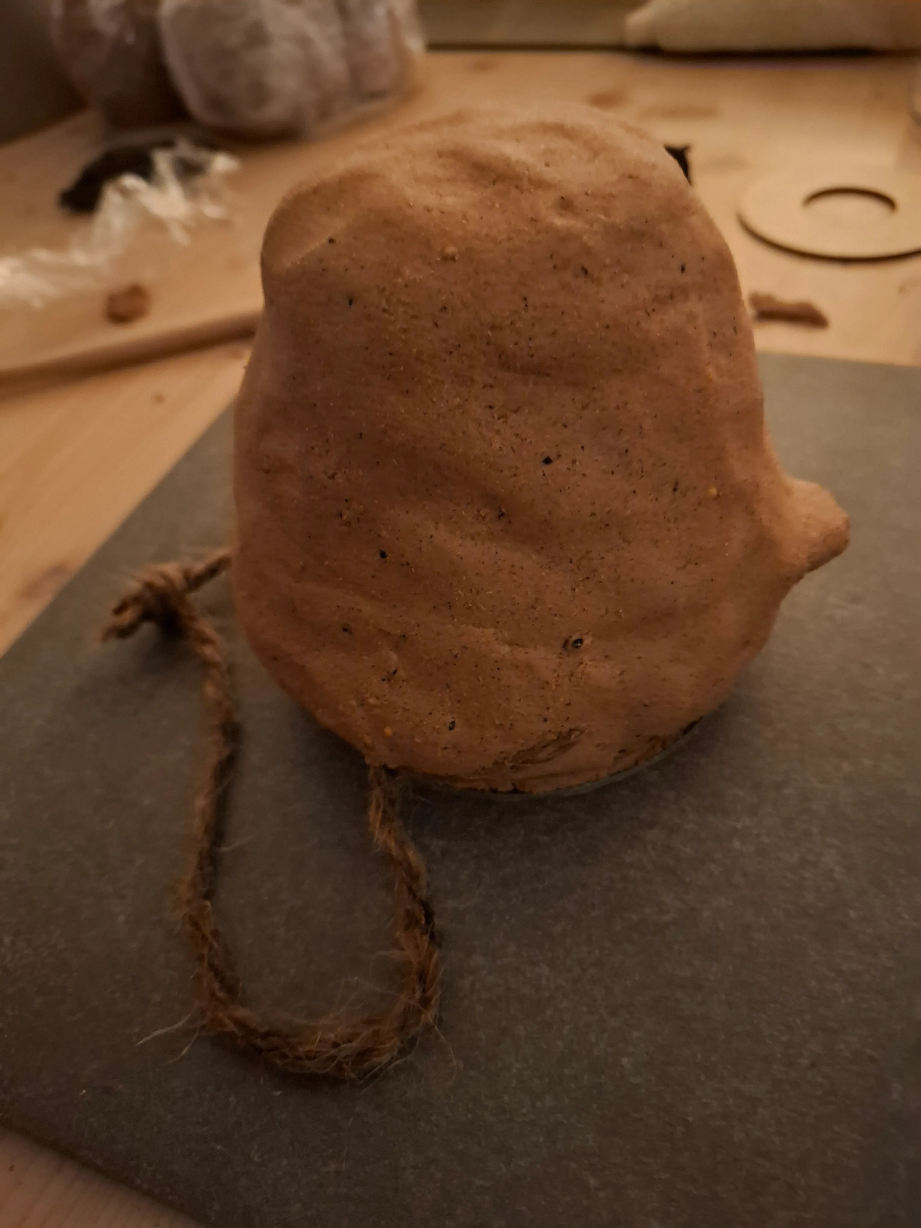 Braunes Tongegenstand mit Seil auf Tisch.