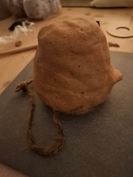 Braunes Tongegenstand mit Seil auf Tisch.