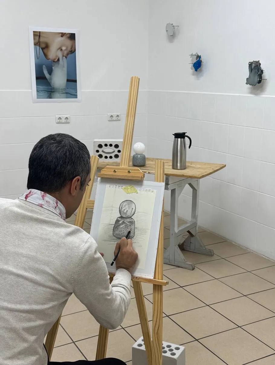 Person drawing on easel in tiled room.