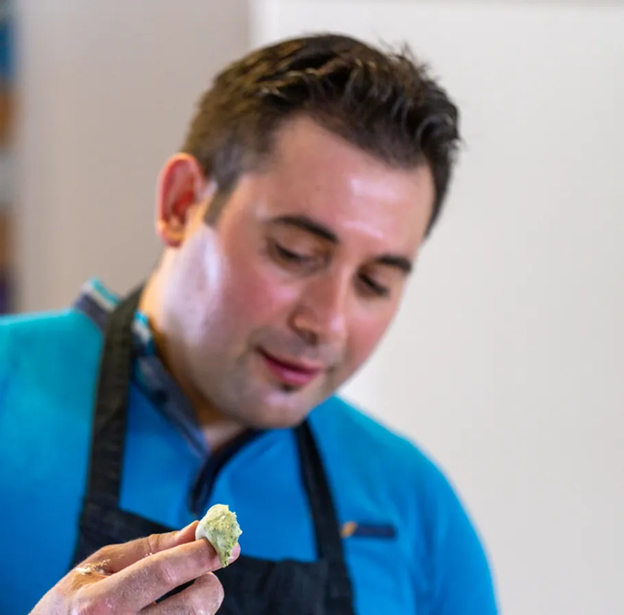 Man holding food, wearing apron, indoors.