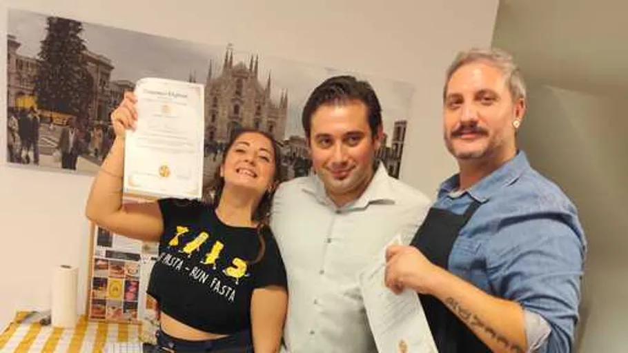 Three people smiling, holding certificates indoors.