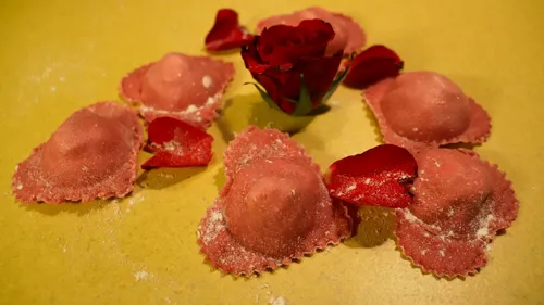 Pink ravioli with rose petals on yellow background.