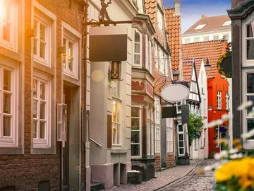 Engpass mit historischen Gebäuden, Geschäfte und blühenden Blumen.