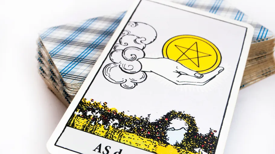 Tarot card with pentacle hand, deck behind.