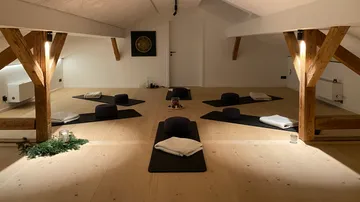 Meditation cushions on mats in peaceful room.