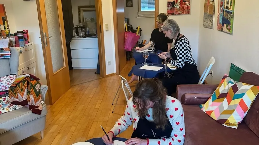 Three women painting in a cozy room.