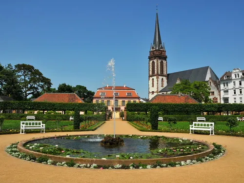 Brunnen sprudelt in einem Garten mit historischen Gebäuden.