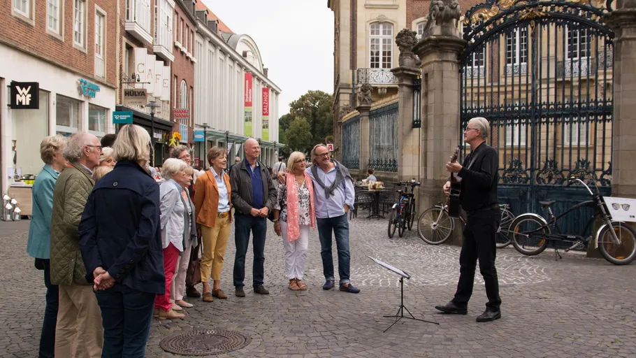 Musiker spielt Gitarre für aufmerksame Gruppe im Freien.