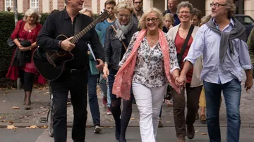 Group of people walking happily on a sidewalk.