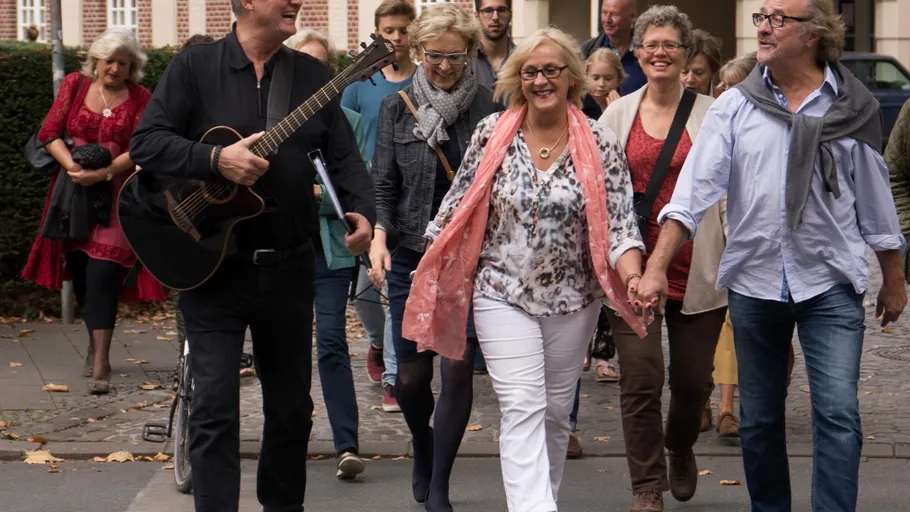 Gruppe von Menschen läuft fröhlich auf dem Bürgersteig.
