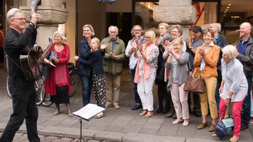 Musician performs outdoors, crowd applauds enthusiastically.
