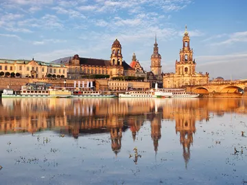 Schiffe spiegeln sich im Wasser vor historischer Architektur.