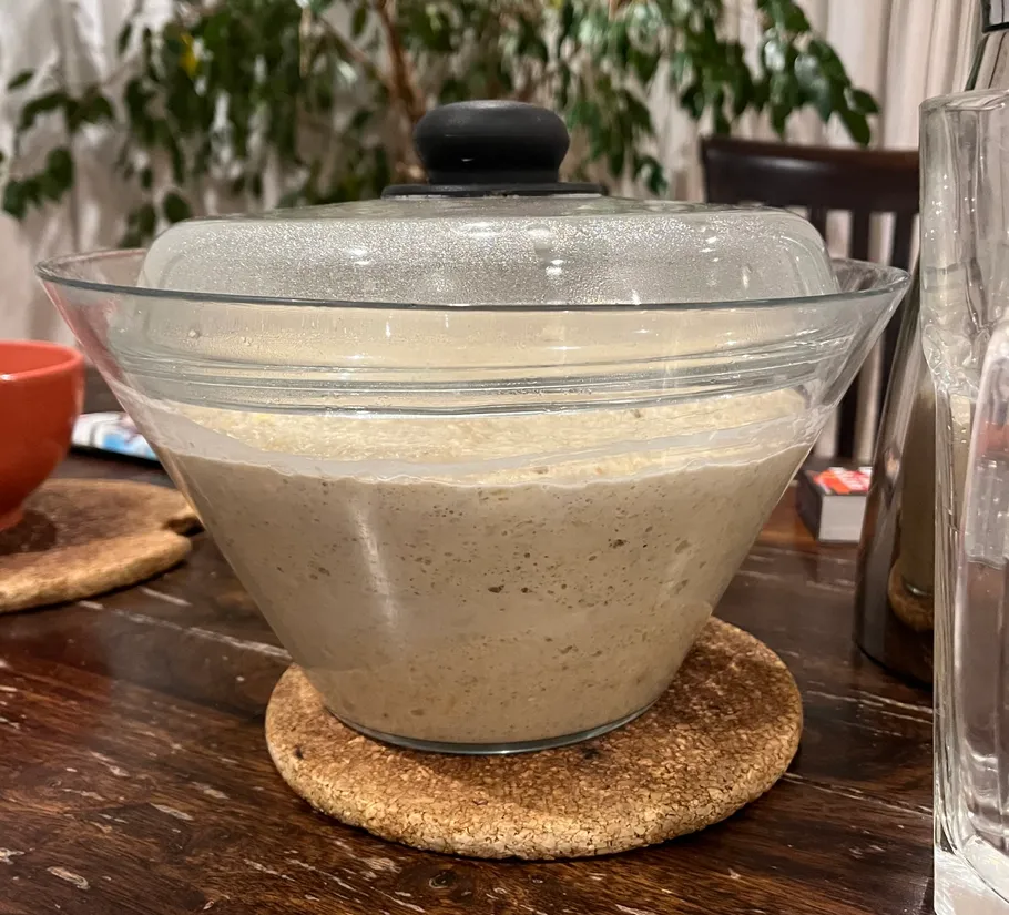 Dough rising in glass bowl on table.