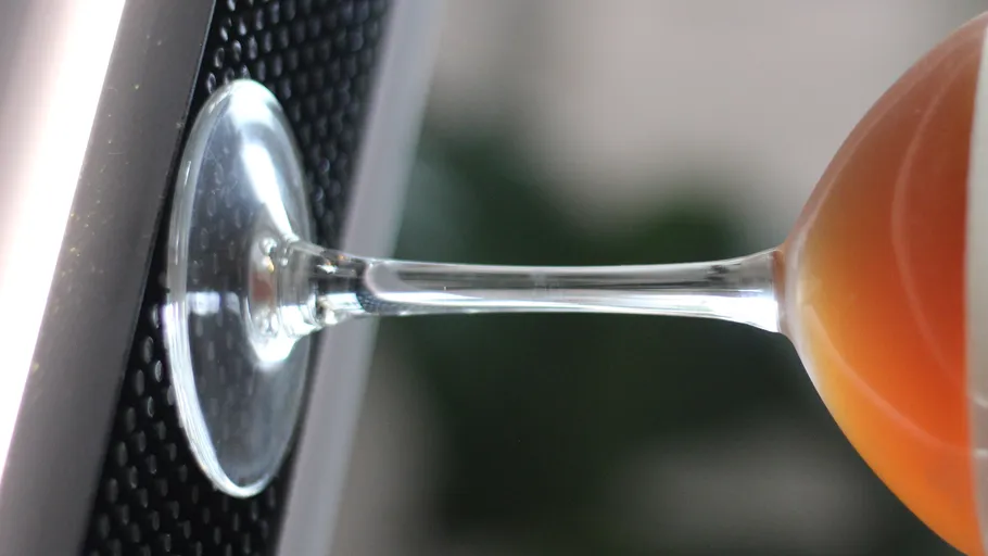 Glass of orange drink on speaker surface.