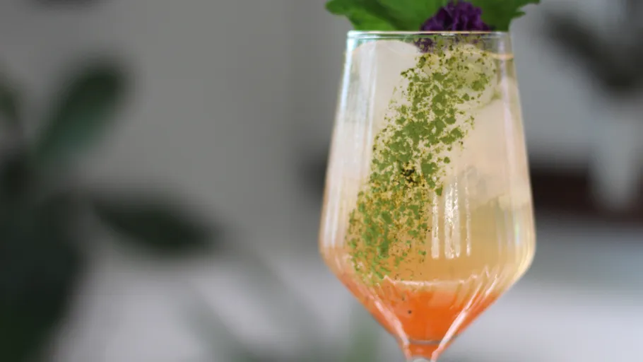 Colorful cocktail with garnish in elegant glass.