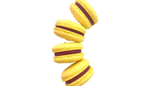 Yellow macarons stacked with red filling.