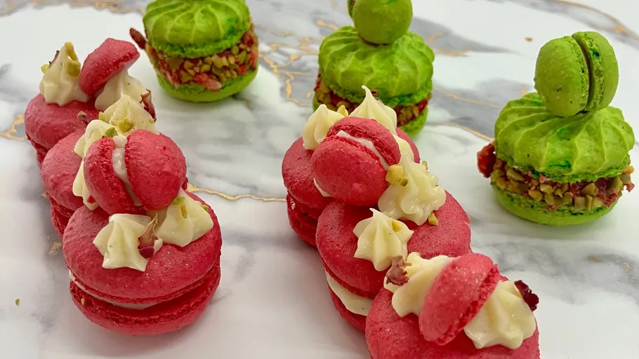 Colorful macarons with cream filling on marble.