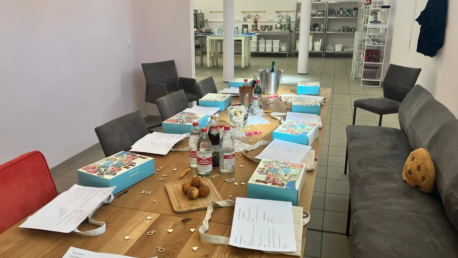 Gedeckter Tisch mit Geschenktüten und Snacks im Raum.