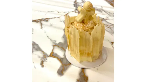 Cake topped with gingerbread man on marble table.
