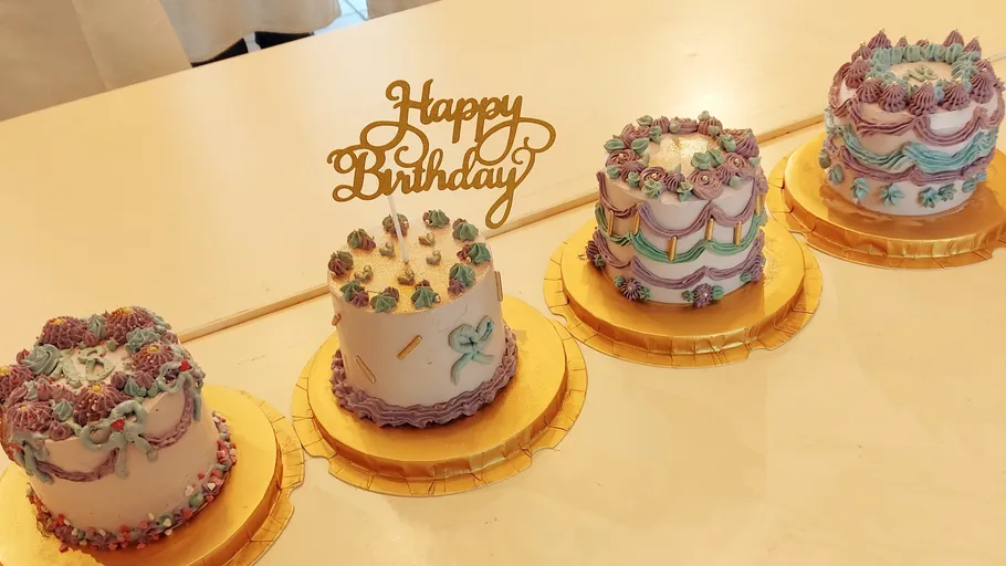 Four decorated cakes with 'Happy Birthday' topper.