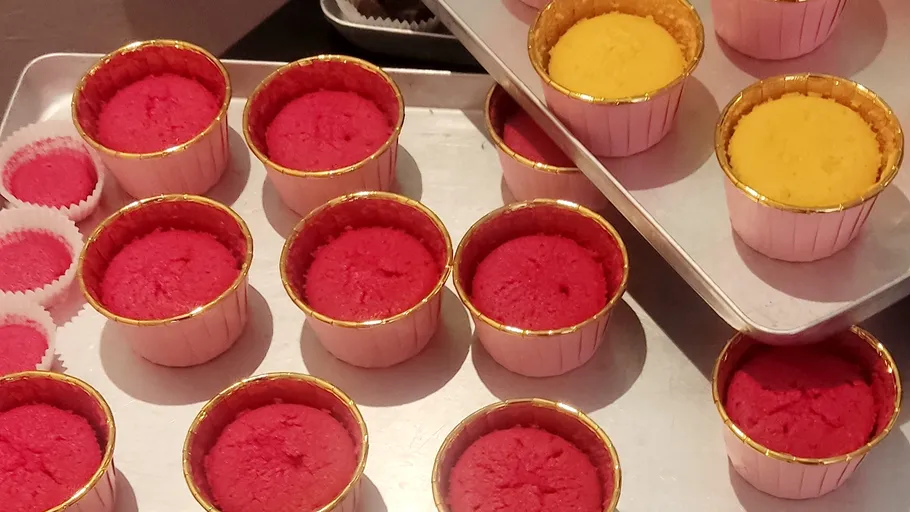 Bunte Cupcakes auf Metallbackblechen angeordnet.