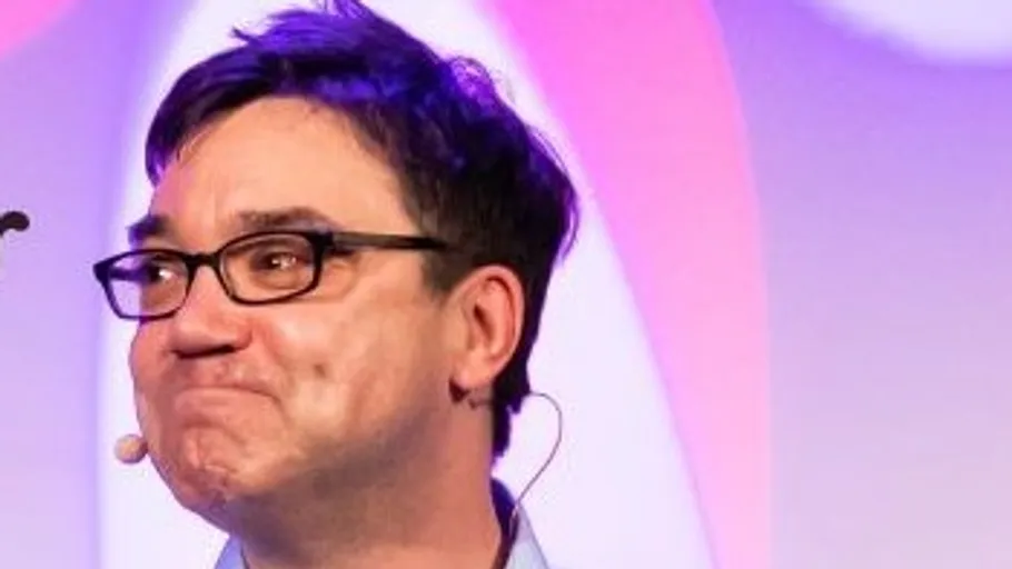 Person with glasses speaking on stage.