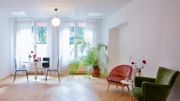 Heller Raum mit Stühlen, Tisch und Pflanzen.