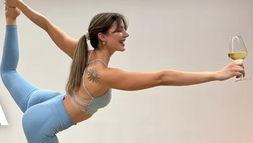 Frau in Yoga-Pose hält Weinglas.