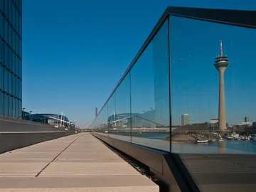Glaswand reflektiert den Fernsehturm und den klaren Himmel.