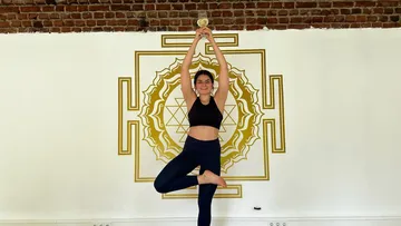 Woman holding trophy in yoga pose indoors.
