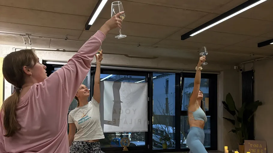 Drei Frauen heben Gläser im Yogastudio.
