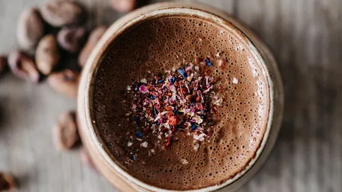 Cup of chocolate with flower garnish on top.