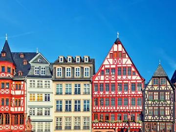 Colourful half-timbered houses stand under clear skies.