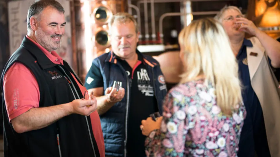 Personen probieren Getränke in Brennereiumgebung.