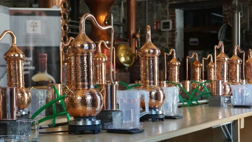 Copper stills arranged on a distillery table.