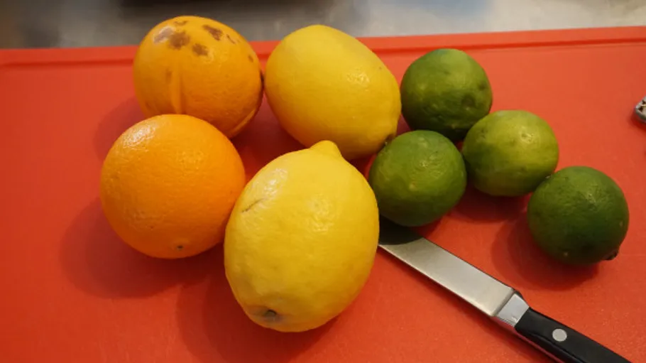 Citrus fruits and knife on red cutting board.
