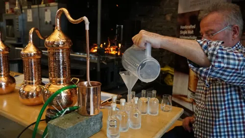 Man pouring liquid into bottles in distillery.
