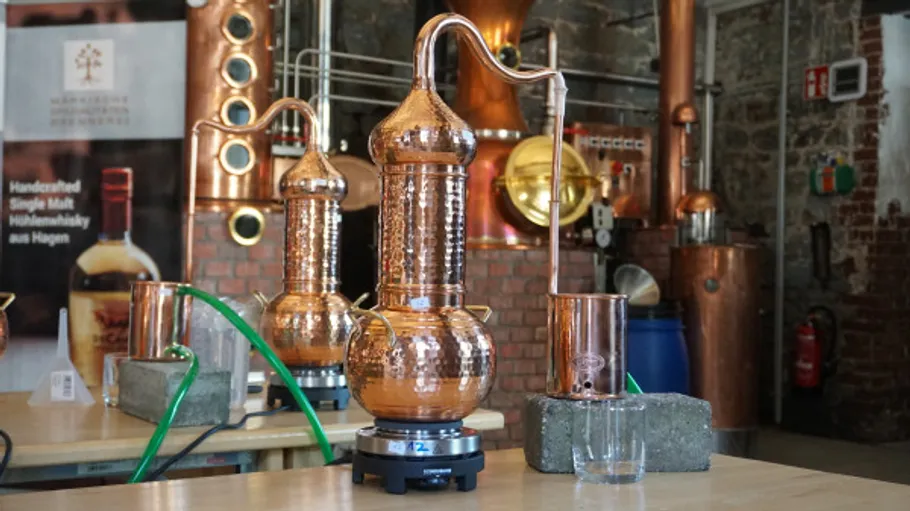 Copper stills on tables in a distillery.