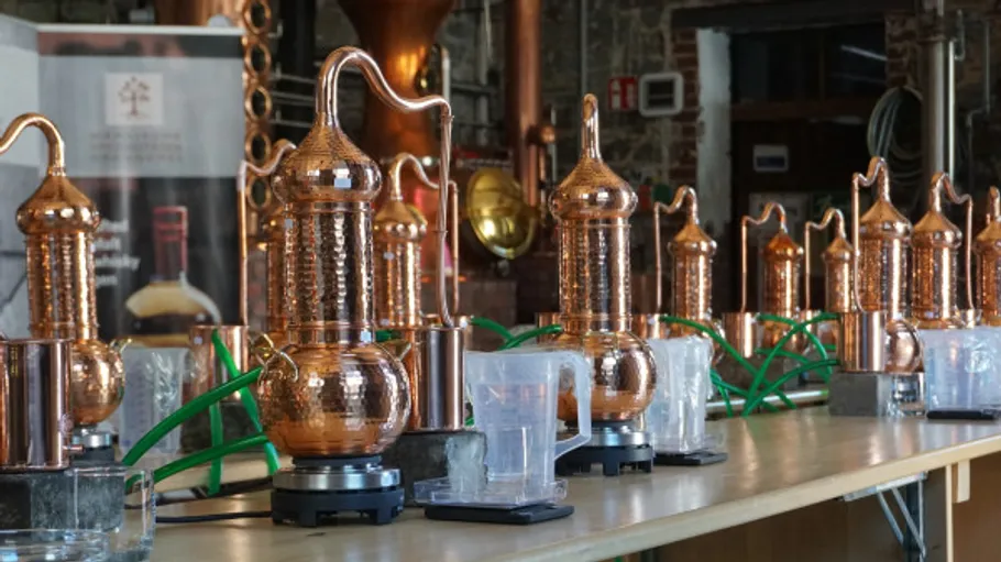 Copper distillers aligned on workshop table.